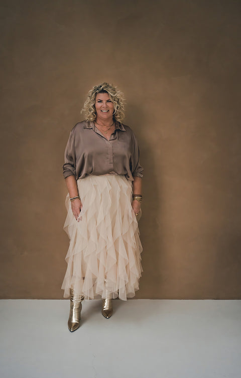 Claudette Jacobs, auteur van Soulmission Kaartendeck en Inspiratie kaarten. Tevens business coach en lifestyle coach wat zorgt voor transformaties voor een bruine muur met witte lange rok.