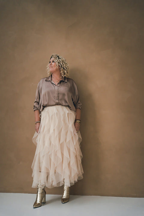 Claudette Jacobs, auteur van Soulmission Kaartendeck en Inspiratie kaarten. Tevens business coach en lifestyle coach wat zorgt voor transformaties voor een bruine muur met witte lange rok.